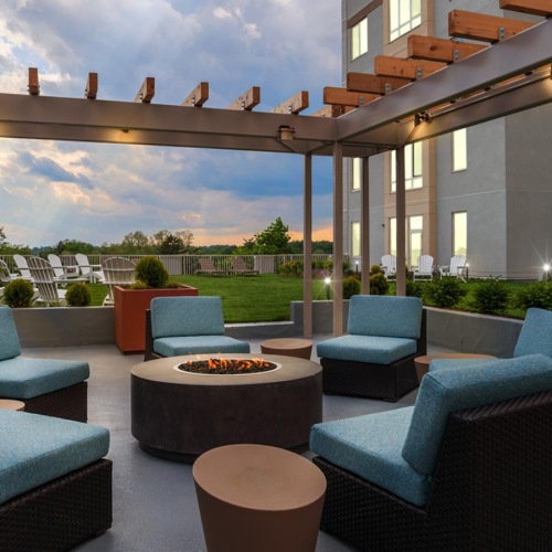 an outdoor lounge with a fire pit and chairs